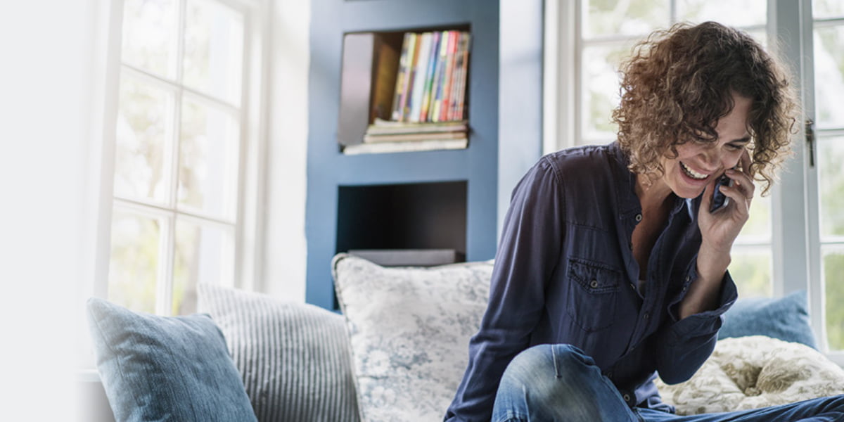 woman laughing on phone on sofa